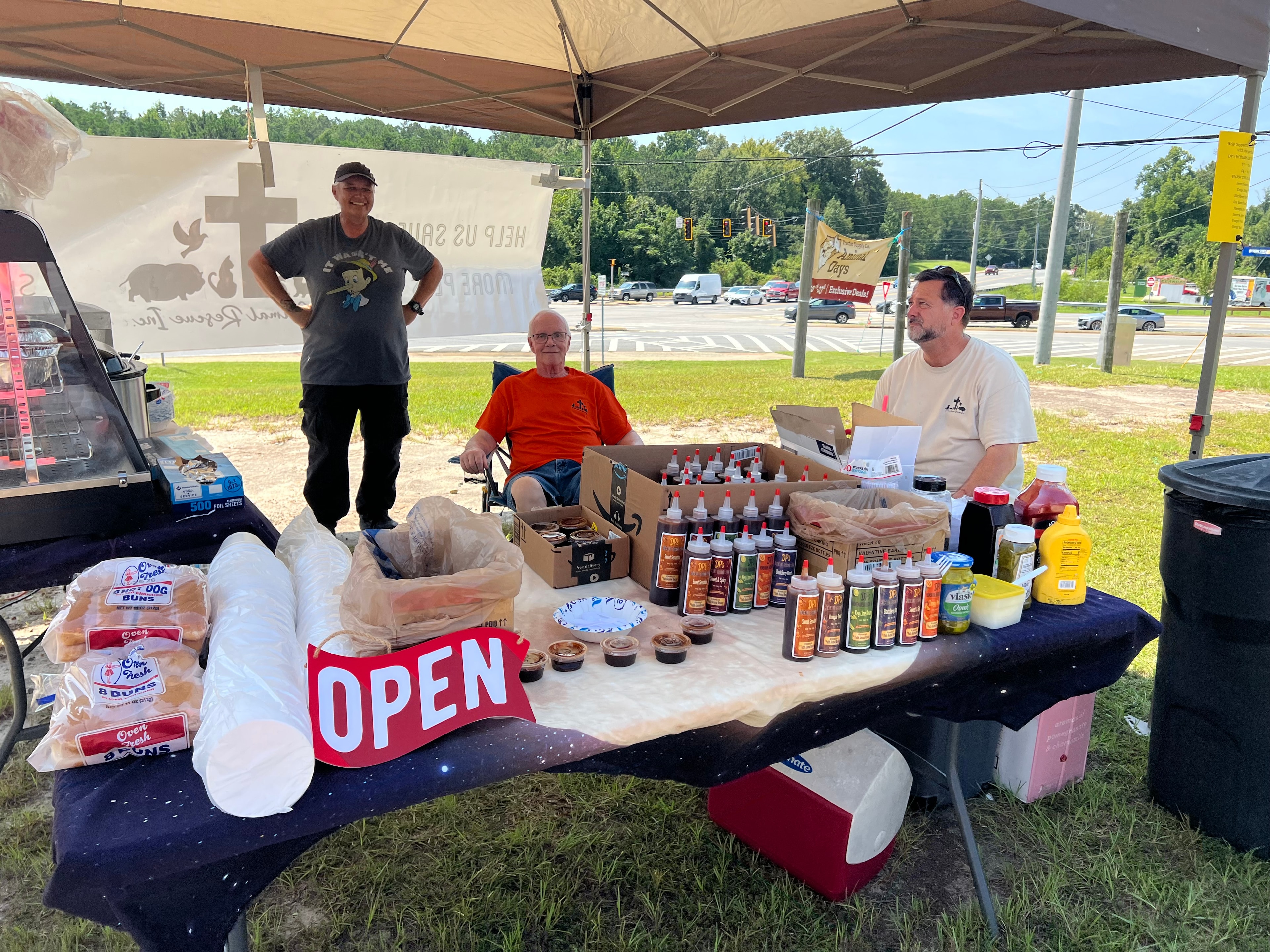 Faith Animal Rescue BBQ fundraiser booth with volunteers and sauce display