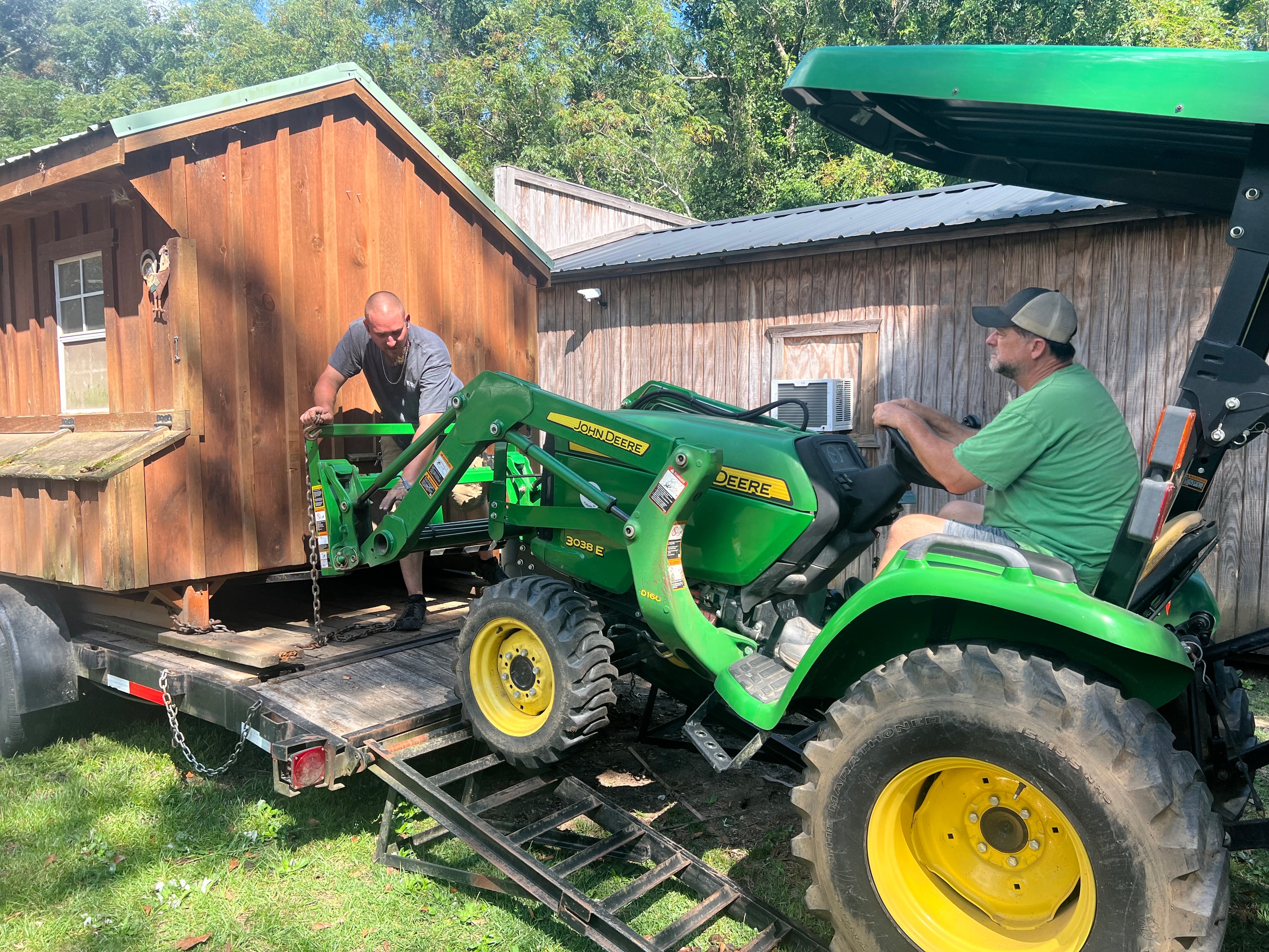 Volunteers using John Deere tractor to move a shed for Faith Animal Rescue