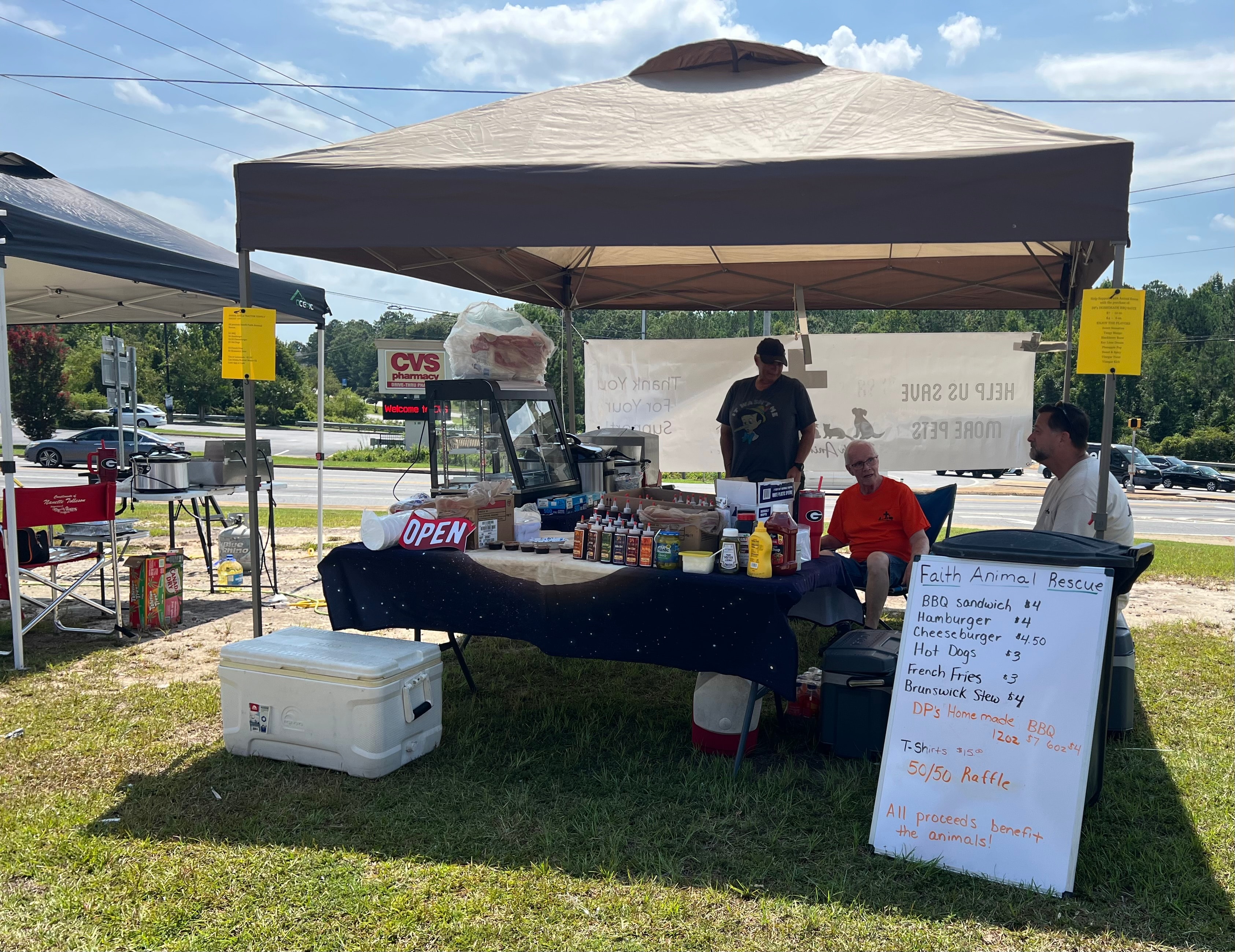 Faith Animal Rescue BBQ fundraiser booth with menu board showing all proceeds benefit the animals