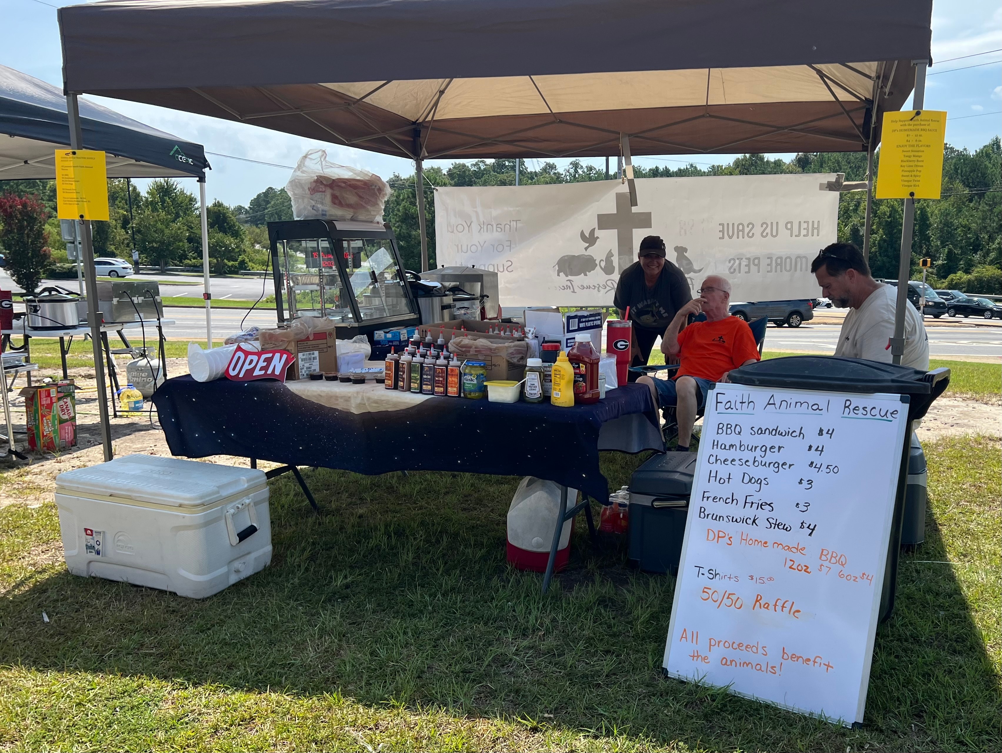 Faith Animal Rescue BBQ fundraiser with volunteers and menu board